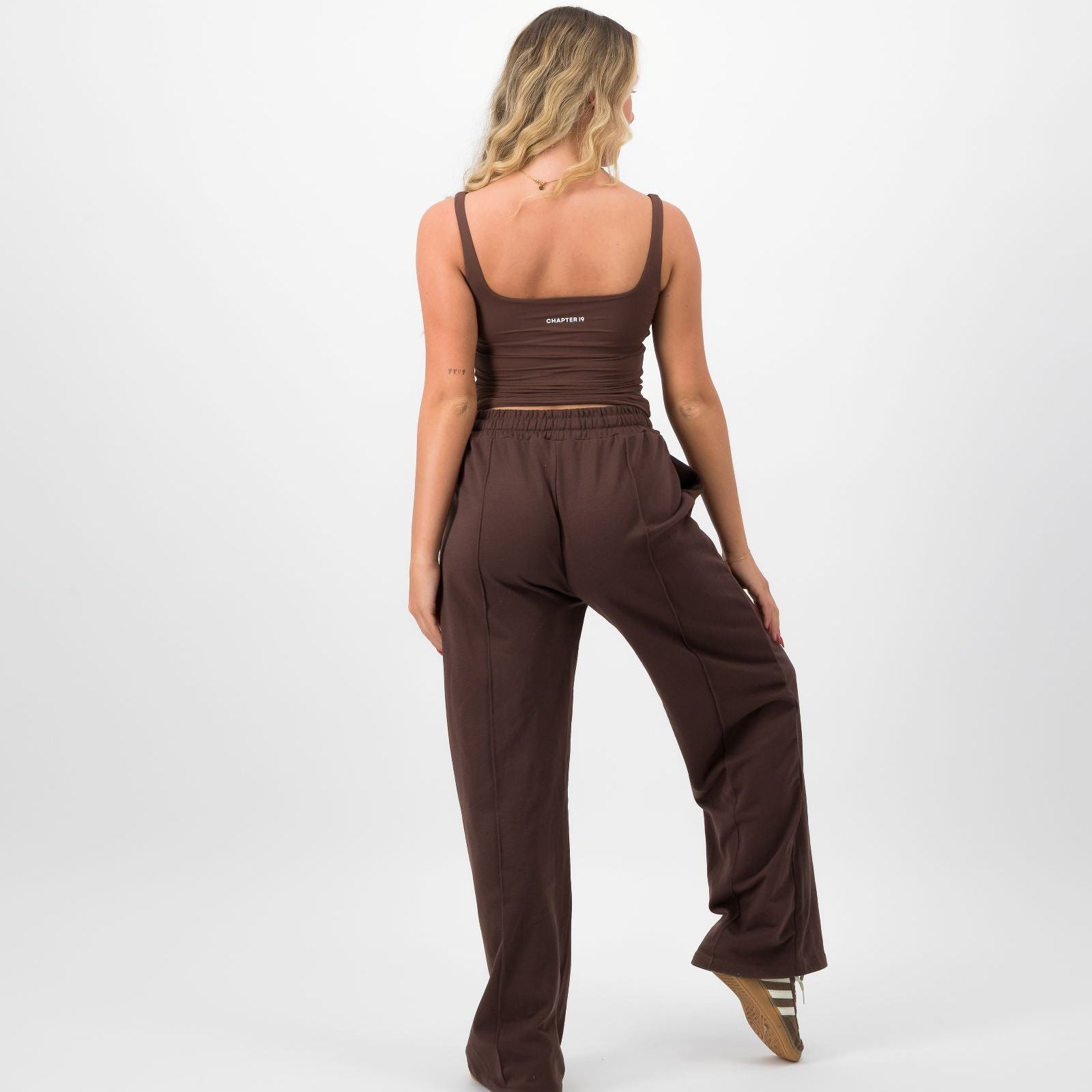 Woman wearing a brown jumpsuit on a white background