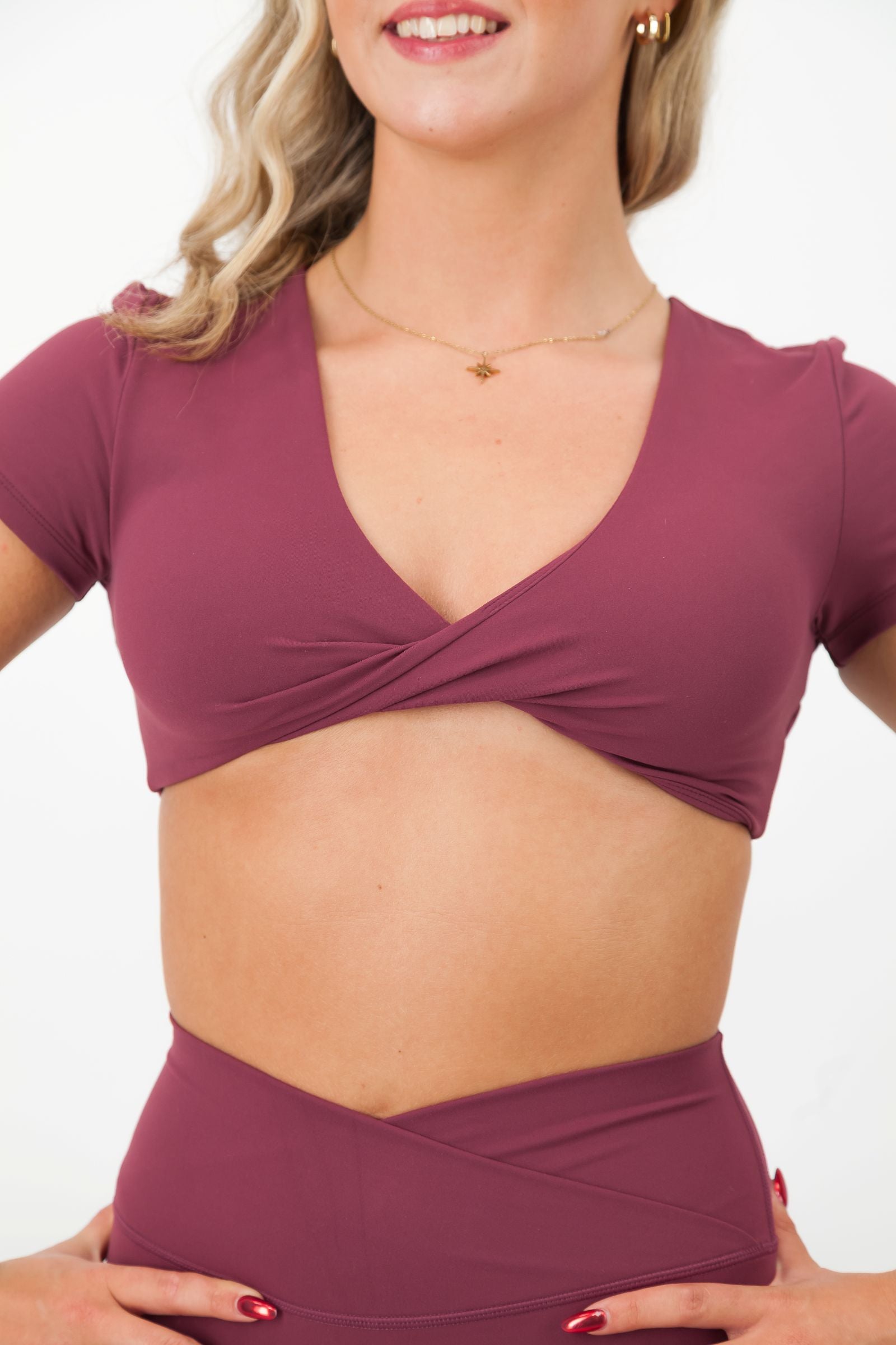 Woman wearing a purple crop top and leggings on a white background