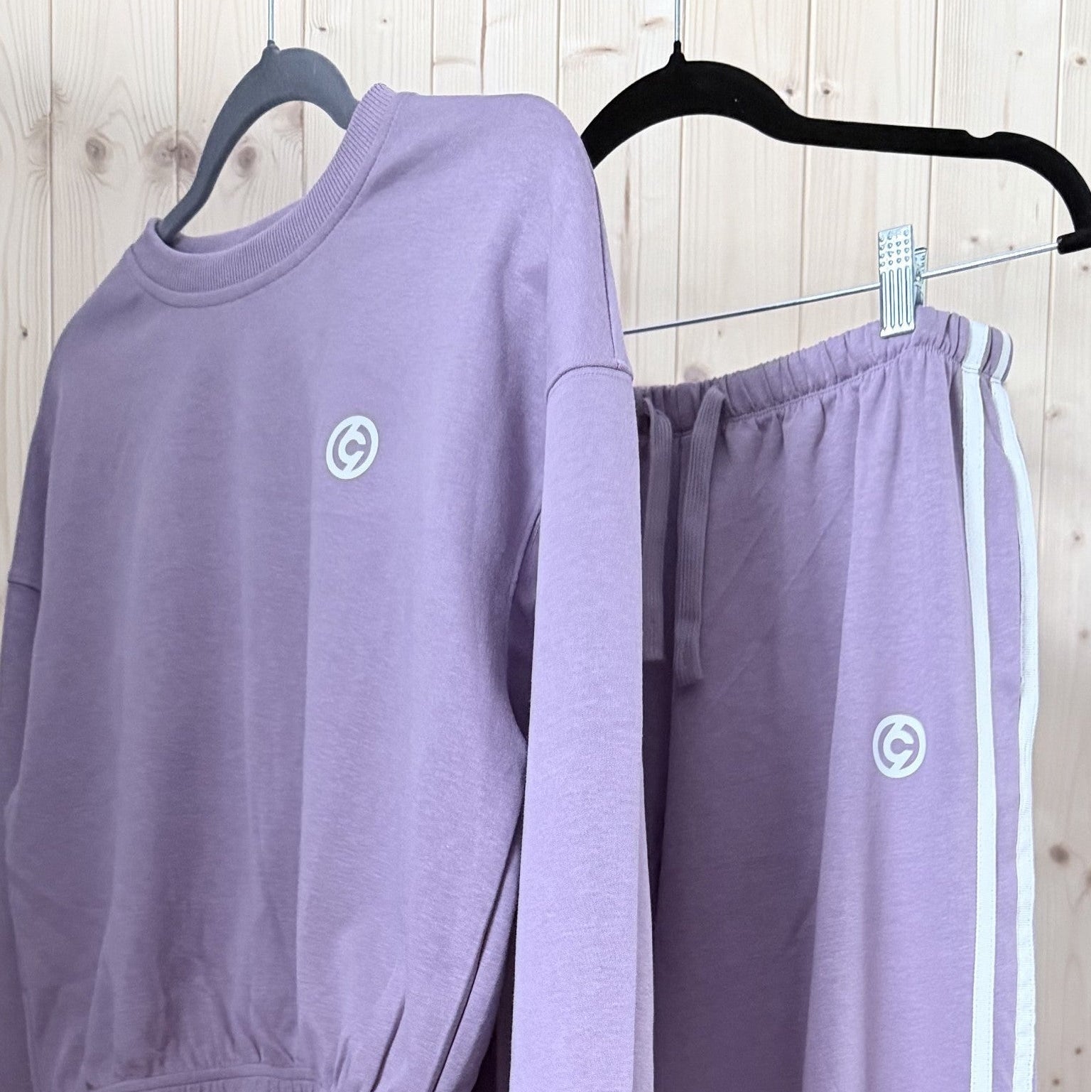 Purple tracksuit with a logo on hangers against a wooden background