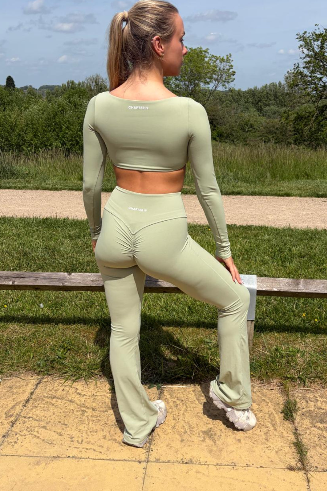 Woman in green athletic wear standing outdoors on a sunny day.