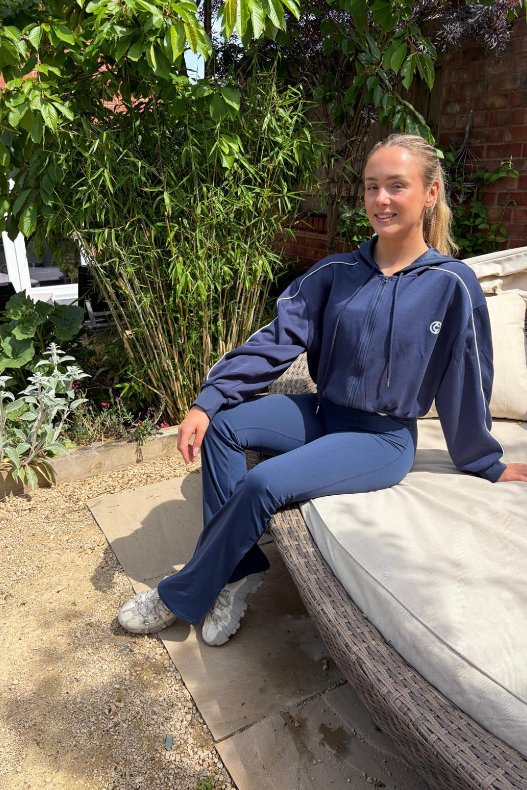 Woman in blue tracksuit sitting on a patio chair outdoors