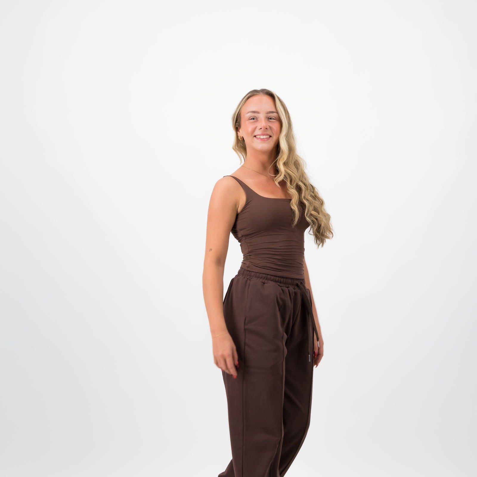 Woman wearing a brown jumpsuit on a white background