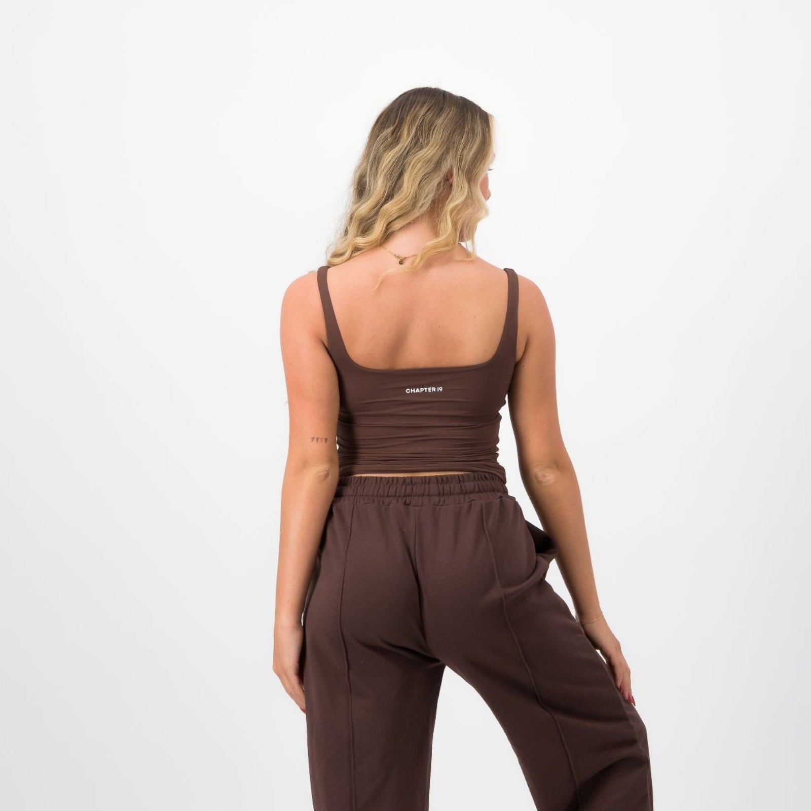 Woman wearing a brown jumpsuit on a white background