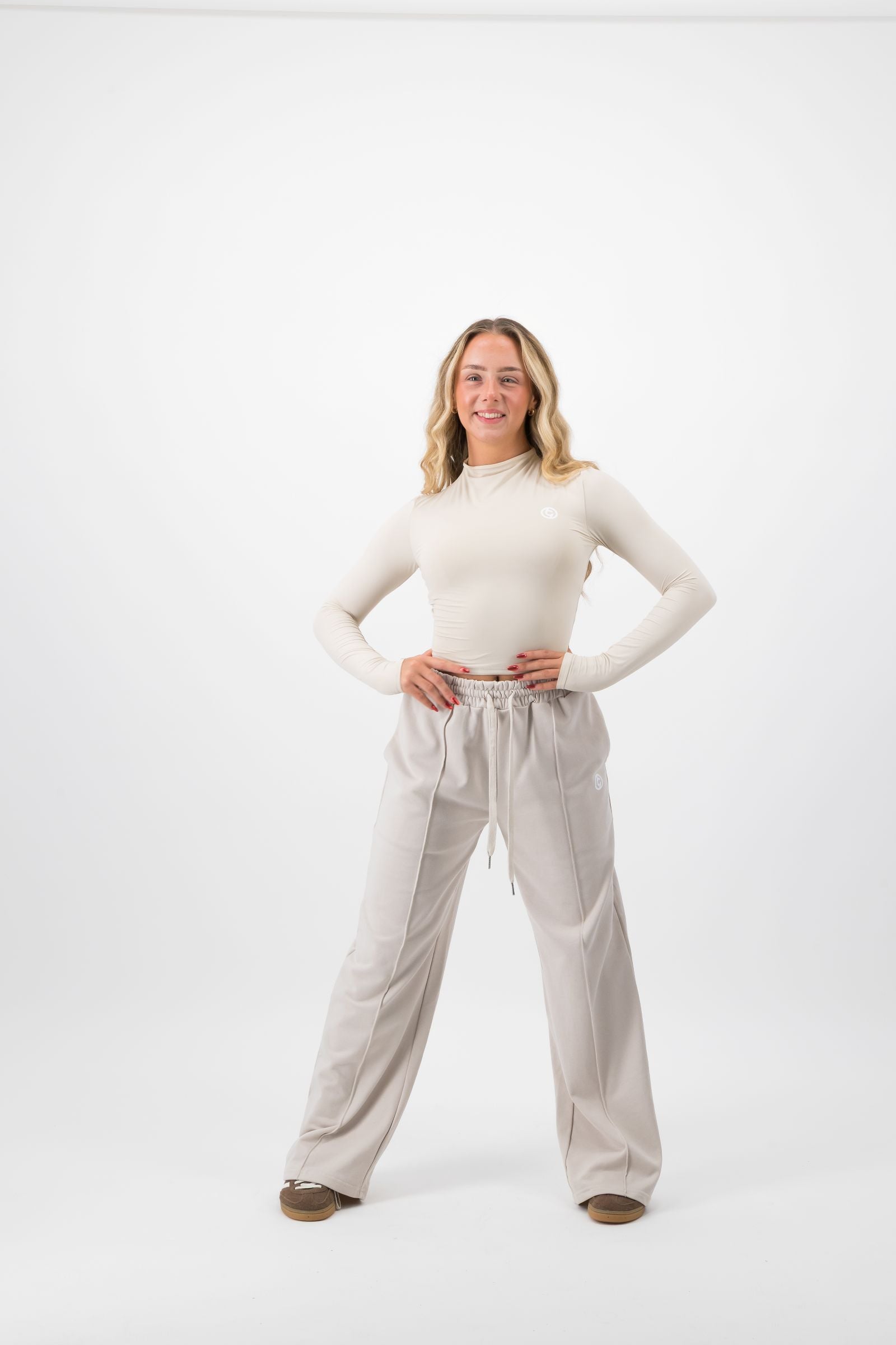 Woman wearing a white top and beige pants on a white background