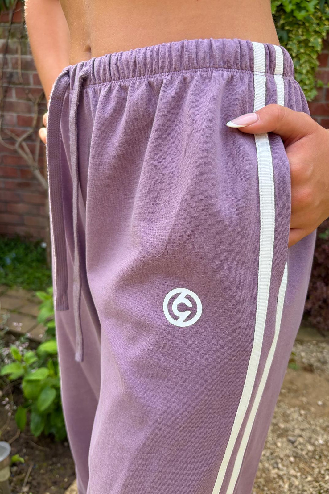 Purple tracksuit pants with a logo on a person outdoors