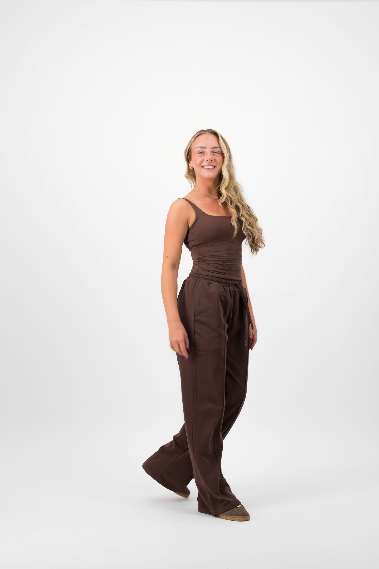 Woman wearing a brown jumpsuit on a white background